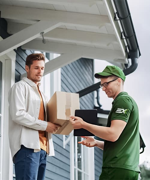 Courier in green uniform hands a cardboard box to a man while holding a tablet.